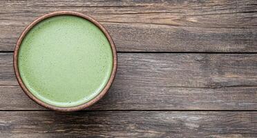 green matcha tea drink in wooden bowl on rustic table photo