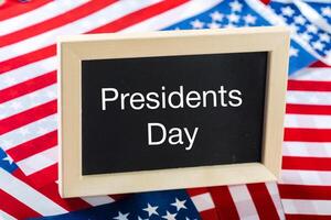 the text happy presidents day written in a chalkboard and a flag of the United States photo