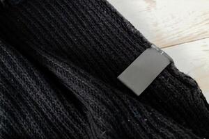 Stack of wool knitted warm sweater and white label for text photo