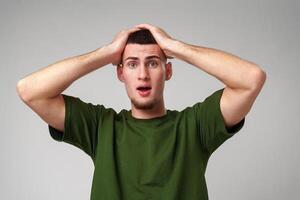 Young Man Reacts in Shock and Disbelief With Hands on Head Against a White Background photo