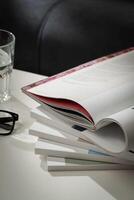 Stack of White Paperbacks and Glass of Water on White Table photo