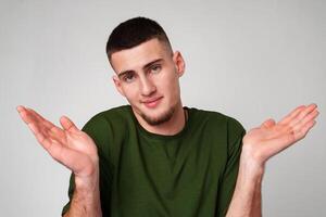 Young Man Wearing Green T-Shirt Gesturing With Both Hands in Front of a Plain White Background photo