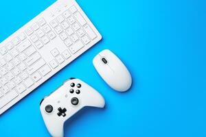 Computer keyboard and joystick on blue background top view photo