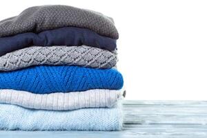 Stack of various sweaters isolated on white background photo