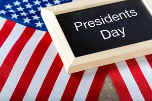 the text happy presidents day written in a chalkboard and a flag of the United States photo