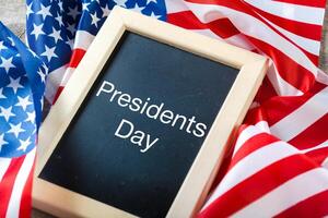 the text happy presidents day written in a chalkboard and a flag of the United States photo