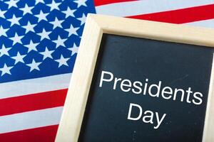 the text happy presidents day written in a chalkboard and a flag of the United States photo