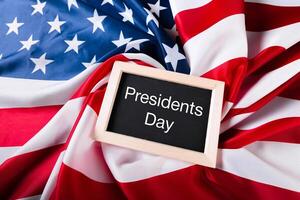 the text happy presidents day written in a chalkboard and a flag of the United States photo