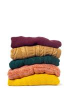 Stack of various sweaters isolated on white background photo