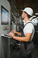 Factory male bearded worker is programming a CNC milling machine with copy space photo