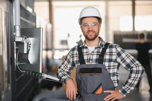 Factory male bearded worker is programming a CNC milling machine with copy space photo