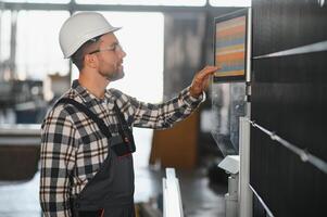 Factory male bearded worker is programming a CNC milling machine with copy space photo