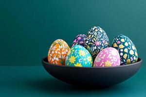 Colorful hand-painted Easter eggs with folk art patterns in a dark bowl on a deep teal backdrop photo
