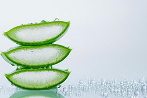 Fresh aloe vera leaves sliced open to showcase gel with hydration droplets on a white background photo