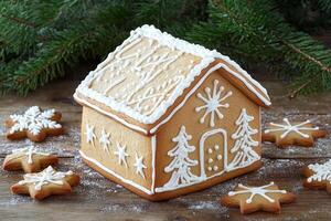 Decorated gingerbread house with festive cookies on a rustic wooden table surrounded by pine branches photo