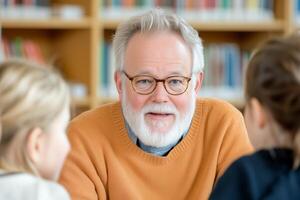 Elderly man with glasses explains concept to students in library with warm lighting and bookshelves photo