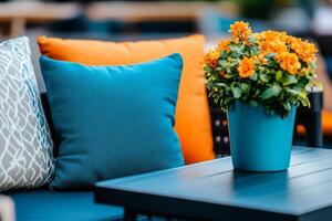 Stylish outdoor patio featuring dark teal furniture, cream cushions, and vibrant orange plants during a sunny afternoon photo