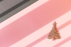 Christmas and New year shiny christmas tree on a pink and gray background with diagonal stripes from the rays of the sun photo