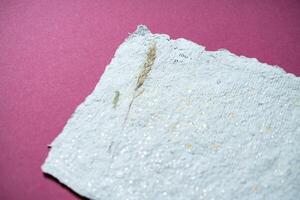 Sheets of recycled paper with dried flowers on pink background. Secondary production. Making paper with your own hands at home. photo