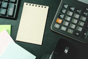 Top view of notebook. Blank paper notepad on office desk table with keyboard and other supplies. Blank notebook page for input the text. copy space, flat lay. photo