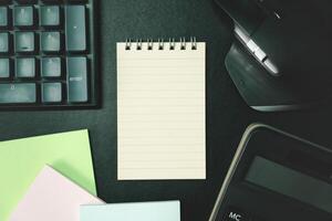 Top view of notebook. Blank paper notepad on office desk table with keyboard and other supplies. Blank notebook page for input the text. copy space, flat lay. photo
