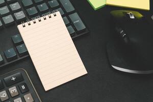 Top view of notebook. Blank paper notepad on office desk table with keyboard and other supplies. Blank notebook page for input the text. copy space, flat lay. photo