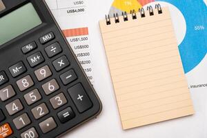 Blank note on desk with monthly budget graph. Financial data analyzing. Working on desk with using calculator, finance accounting. Copy space. photo