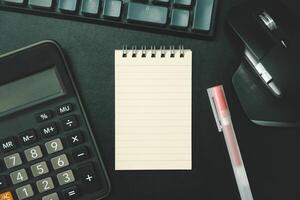 Top view of notebook. Blank paper notepad on office desk table with keyboard and other supplies. Blank notebook page for input the text. copy space, flat lay. photo
