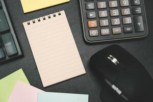 Top view of notebook. Blank paper notepad on office desk table with keyboard and other supplies. Blank notebook page for input the text. copy space, flat lay. photo
