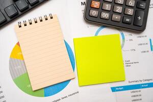 Blank note on desk with monthly budget graph. Financial data analyzing. Working on desk with using calculator, finance accounting. Copy space. photo