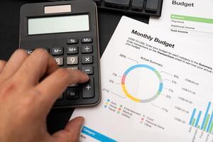 Financial data analyzing hand counting on calculator in office on desk with monthly budget graph. working on desk with using calculator, finance accounting. photo