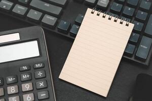 Top view of notebook. Blank paper notepad on office desk table with keyboard and other supplies. Blank notebook page for input the text. copy space, flat lay. photo