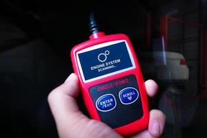 Handheld engine diagnostic obd tool in use for car fixing , Car repair concept photo