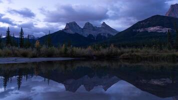 Time Lapse of View of Three Sisters Mountains, Canmore, Alberta, Canada with Reflection in Lake at Sunrise video
