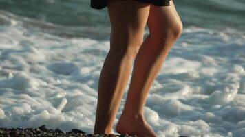 Legs Beach Waves Woman Walking Shoreline - Closeup of a woman's legs walking on a beach with waves crashing around them. video
