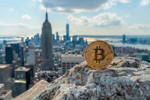 Bitcoin cryptocurrency coin on a rock with the New York City skyline, including the Empire State Building. photo