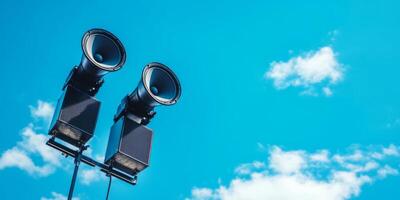 A pair of loudspeakers is mounted high on a sturdy pole against a clear blue sky, serving as an essential communication tool for public safety alerts and important announcements in urban areas photo