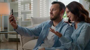 Caucasian happy couple family waving hello showing thumb up talking conversation virtual call mobile phone conference chat blog vlog in social media bloggers speak at home with smartphone app photo