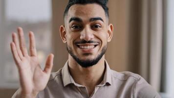 Hispanic handsome business man millennial wave hand greet look at camera arab friendly guy record lifestyle blog provide distance tutorial educational course use internet online web application photo