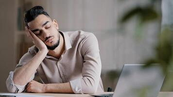 Sleepy tired hispanic man employee male businessman dreamer sleeping at home office workplace napping has rest arabian lazy student overwhelmed unhealthy guy feeling exhausted after hard computer work photo