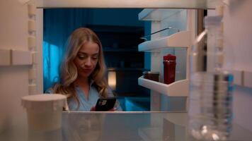 Point of view POV inside refrigerator Caucasian girl hungry woman open fridge at home kitchen look at empty shelves order food products delivery with mobile phone app online service web store shopping photo