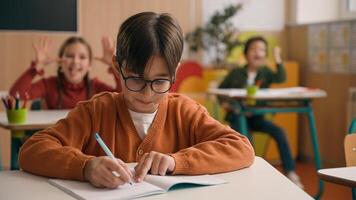 Caucasian little boy kid schoolboy nerd in glasses write task class lesson school education angry children cruel throw crumpled paper balls abuse abusing bullying classmates studying problem mock photo