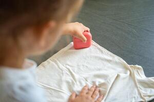 Back view of little girl with a stamp with a name for signing children's things. Identification of personal clothing. High quality photo