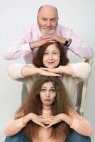 A creative family portrait of elderly parents and an adult daughter on a gray background. photo