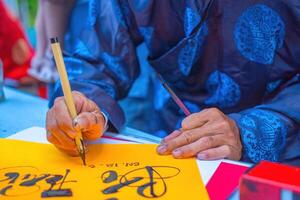 Vietnamese scholar writes calligraphy. Calligraphy festival is a popular tradition during Tet holiday. Writing couplets for Spring Festival, new year. photo