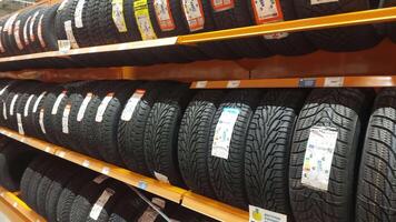 linhas do pneus estão ordenadamente arranjado em prateleiras dentro a auto partes loja. cada pneu é etiquetado com detalhes sobre Tamanho e especificações, fornecendo clientes com uma Largo seleção para seus veículos. video