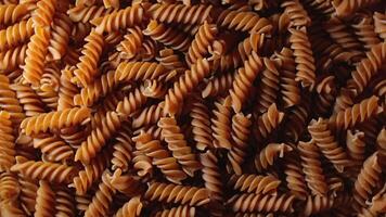 Uncooked Whole Grain Fusilli Pasta. A Culinary Canvas of Whole Wheat Spirals, Textured Background - Top View, Rotating. Turning Whole Grain Twisted Dry Pasta. Whole Wheat Raw Macaroni - Rotation video