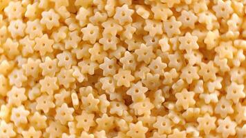 Uncooked Stelline Pasta. A Culinary Canvas of Stelle Macaroni, Creating a Lively and Textured Background for Gourmet Cooking - Top View, Rotating. Turning Dry Pasta. Raw Macaroni - Rotation video
