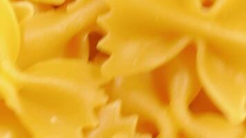 Uncooked Farfalle Pasta. A Culinary Canvas of Bow-Tie Macaroni, Creating a Lively and Textured Background for Gourmet Cooking - Top View, Rotating. Turning Dry Pasta. Raw Macaroni - Angular Rotation video