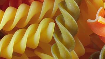 Uncooked Vibrant Colored Fusilli Pasta. A Mesmerizing Culinary Canvas of Multicolored Spirals, Textured Background - Rotating. Turning Colored Dry Pasta. Raw Macaroni - Rotating video